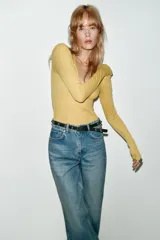 Jeans de tiro alto color azul claro, con cinco bolsillos y pernera recta que se estrecha hacia el tobillo. Incluye un cinturón negro con detalles metálicos.