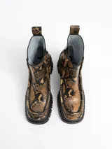 Botín de cuero con estampado de piel de serpiente en tonos ocre y negro, con puntera cuadrada, cierre lateral con cremallera, suela track de goma y tacón cuadrado.