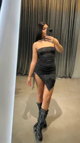 Vestido corto negro strapless con brillos y corte asimétrico.