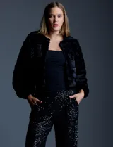 Chaqueta corta (crop) de piel sintética negra, con mangas largas abullonadas y abertura frontal.