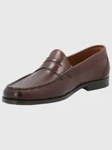 Zapato mocasín de cuero color marrón, con detalle de antifaz y suela de cuero y goma.
