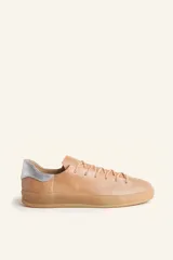 Zapatillas bajas blancas de cuero vacuno con detalle de refuerzo de gamuza color borgoña en el talón y suela de goma color caramelo.