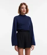 Suéter corto azul marino de punto liviano, con cuello alto, manga larga y puños ajustados.