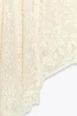 Falda corta de encaje color crema con forro interior. Presenta cintura elástica y bajo asimétrico con terminación en picos.