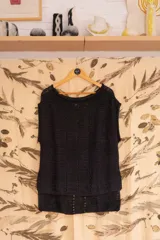 Chaleco negro tejido a mano en dos agujas con hilado 100% baby alpaca, ligeramente oversize, de hombros anchos y cuello tipo bote, con puntos calados en frente y espalda y tajos a los lados en el bajo.