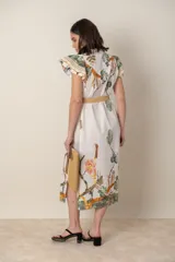 Vestido midi camisero de algodón color natural con estampado de flores, animales y ramas en tonos rojo, marrón, verde y azul. Tiene cuello mao, mangas cortas con volados, bolsillos laterales y cinturón de soga color beige.