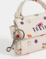 Monedero de cuerina color crudo con estampado de motivos japoneses y la palabra "Tokyo". Tiene forma de bolso con manija superior, solapa con broche a presión y mosquetón lateral.