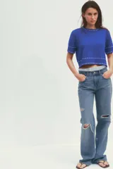 Top azul de tejido de punto con cuello redondo y manga corta. Detalle de pespuntes blancos a contraste en cuello, mangas y ruedo.