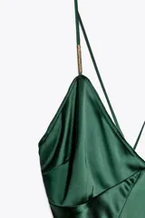 Vestido midi verde esmeralda de satén, con escote en pico, tirantes finos regulables con apliques dorados y cierre lateral con cremallera oculta.