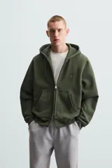 Sudadera negra con capucha ajustable, corte relaxed fit, confeccionada en tejido de algodón compacto con interior en rizo. Cuenta con manga larga, bolsillos frontales tipo canguro, acabados en rib y cierre frontal con cremallera.