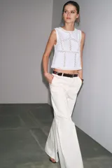 Top blanco de punto elástico con cuello redondo y sisa. Detalle de aplicación de crochet a contraste.