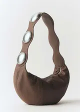 Bolso marrón de cuero con asa de hombro y tachuelas decorativas plateadas.