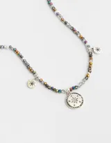 Collar corto de cuentas facetadas grises, doradas y tornasoladas, con dijes redondos plateados con forma de estrella.