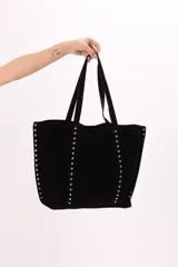 Bolso negro tipo tote bag de gamuza sintética con tachas metálicas plateadas en los bordes.