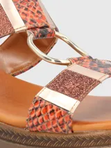 Sandalia con plataforma baja, tiras con estampado de piel de serpiente y detalles metálicos.