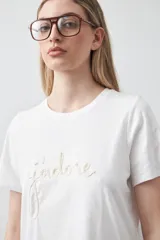 Remera blanca de algodón de manga corta, con cuello redondo y bordado frontal en hilo color beige claro con la palabra "J'adore" en tipografía cursiva.