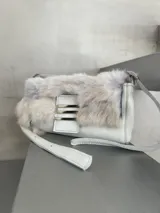 Cartera mini de cuero blanco con solapa de pelo gris y herrajes metálicos plateados.