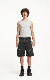 Bermuda negra con recortes blancos y grises, calce oversize, textil liviano, elástico en la cintura, cordón de ajuste, bolsillos delanteros y traseros.