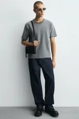 Bandolera negra con acabado engomado, compartimento principal con cierre de cremallera y bolsillo interior con cremallera. Asa de hombro ajustable y extraíble.