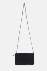 Bolso bandolera negro con tachas plateadas en los bordes. Tiene cierre de cremallera y asa de cadena extraíble.