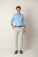 Pantalón de vestir color gris claro, de corte slim fit, con bolsillos laterales y traseros. Se ajusta a la cintura con cinturón de cuero marrón.