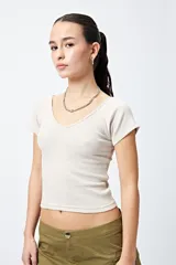 Remera cropped color beige, de ribb con escote en V y mangas cortas con terminación de dobladillo.