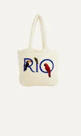 Bolso tipo tote de algodón color crudo con bordado de la palabra "RIO" en azul y apliques de tucán y guacamayo.