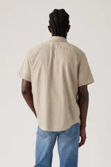 Camisa de manga corta color beige con bolsillo en el pecho y cierre con botones.