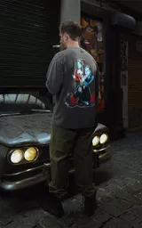 Remera negra con efecto nevado/acid wash, corte oversize, con estampado gráfico en la espalda inspirado en la película 'Bastardos sin gloria' de Tarantino, mostrando personajes con armas y dinamitas.