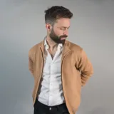 Campera tejida azul marino con cierre frontal, cuello alto y bolsillos laterales.