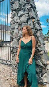 Vestido largo blanco de crepé con escote en V, breteles finos y corte envolvente con volados en el ruedo.