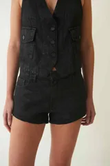 Short negro de tiro bajo, confeccionado en denim 100% algodón con proceso de encuerado. Tiene cuatro bolsillos, pasa cintos, cremallera y botón metálico.
