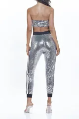 Conjunto plateado de lentejuelas, compuesto por un top bandeau y un pantalón tipo jogging con cintura y puños negros.