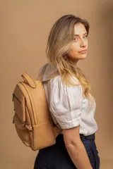 Mochila color marrón de símil cuero con un compartimento principal amplio, bolsillo al frente con cierre, correas ajustables y asa.