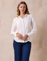 Camisa blanca de manga larga con cuello con solapa y abertura central con botones. Tiene dos bolsillos delanteros aplicados.