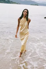 Vestido midi de satén color amarillo pálido, con cuello halter y espalda descubierta.