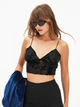 Top corto negro de tirantes finos, con escote en V y borde festoneado. El tejido es transparente con un estampado de terciopelo floral en relieve.