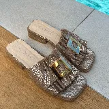 Zuecos con capellada de cuero marrón con estampado de piel de serpiente, fruncido y aplique metálico dorado.