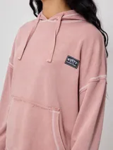 Canguro gris con capucha corta, bolsillo tipo canguro y parche con logo de la marca Rusty en el pecho. Tiene efecto lavado y costuras a la vista.