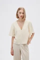 Blusa color crema de viscosa con escote en V y mangas cortas acampanadas.