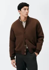 Campera bomber marrón con cierre de botones a presión, cuello mao y bolsillos laterales.