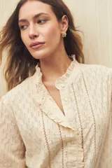 Camisa color crema de manga 3/4 confeccionada en algodón liviano con diseño calado y detalles de encaje en el frente. Su cuello con sutil volado aporta un aire romántico y atemporal.