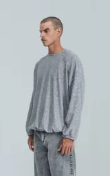 Sweater gris jaspeado de manga larga y cuello redondo, con elástico ajustable en el ruedo inferior.