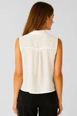 Blusa de algodón color crudo con estampado a cuadros, cuello camisero, cierre frontal con botones, bolsillo en el pecho y corte holgado.