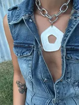 Collar con cadena gruesa plateada y dije abstracto de acrílico y resina color blanco. El dije es desmontable.