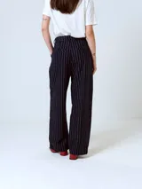 Pantalón de vestir negro con finas rayas verticales blancas, corte recto y tiro alto.