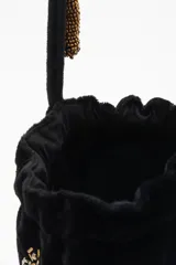 Cartera tipo bombonera negra de terciopelo con bordado de lentejuelas y canutillos dorados con forma de insectos. Tiene cordón de ajuste con borlas de canutillos dorados y correa de mano.