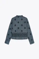 Blusa azul con bordados negros, cuello redondo con escote en pico y cordones ajustables terminados en borlas.