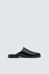 Zueco negro de cuero con punta redondeada y suela plana.