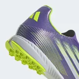 Championes de fútbol Adidas F50 League sin cordones, con exterior Fiberskin y estampado Sprintgrid. El diseño combina colores morado brillante, amarillo neón y blanco. Poseen cuello adaptable, mediasuela de EVA y suela de caucho con taches para césped sintético.